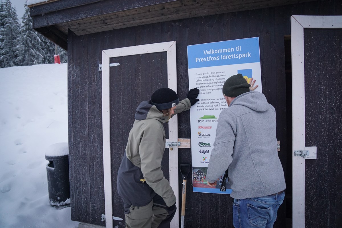 Anders og Christian skrur opp skiltet på utstyrsboden.